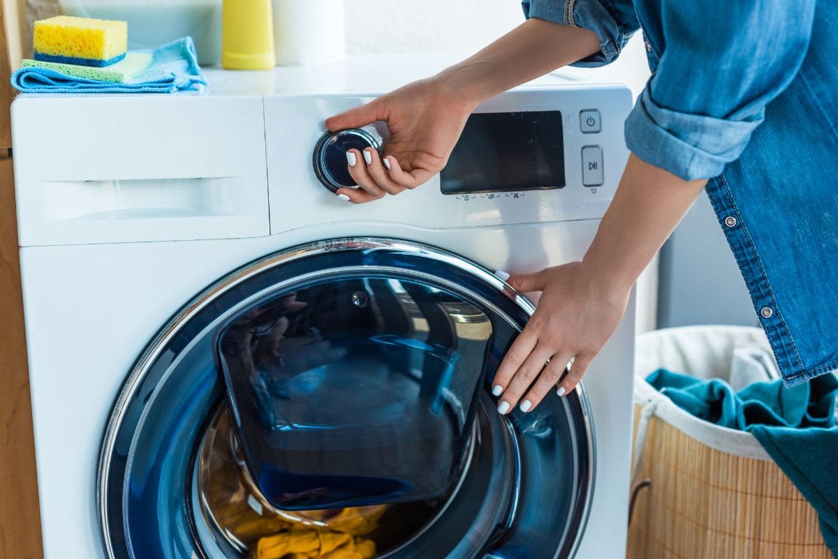 Женщина начинает загружать белье в стиральную машину