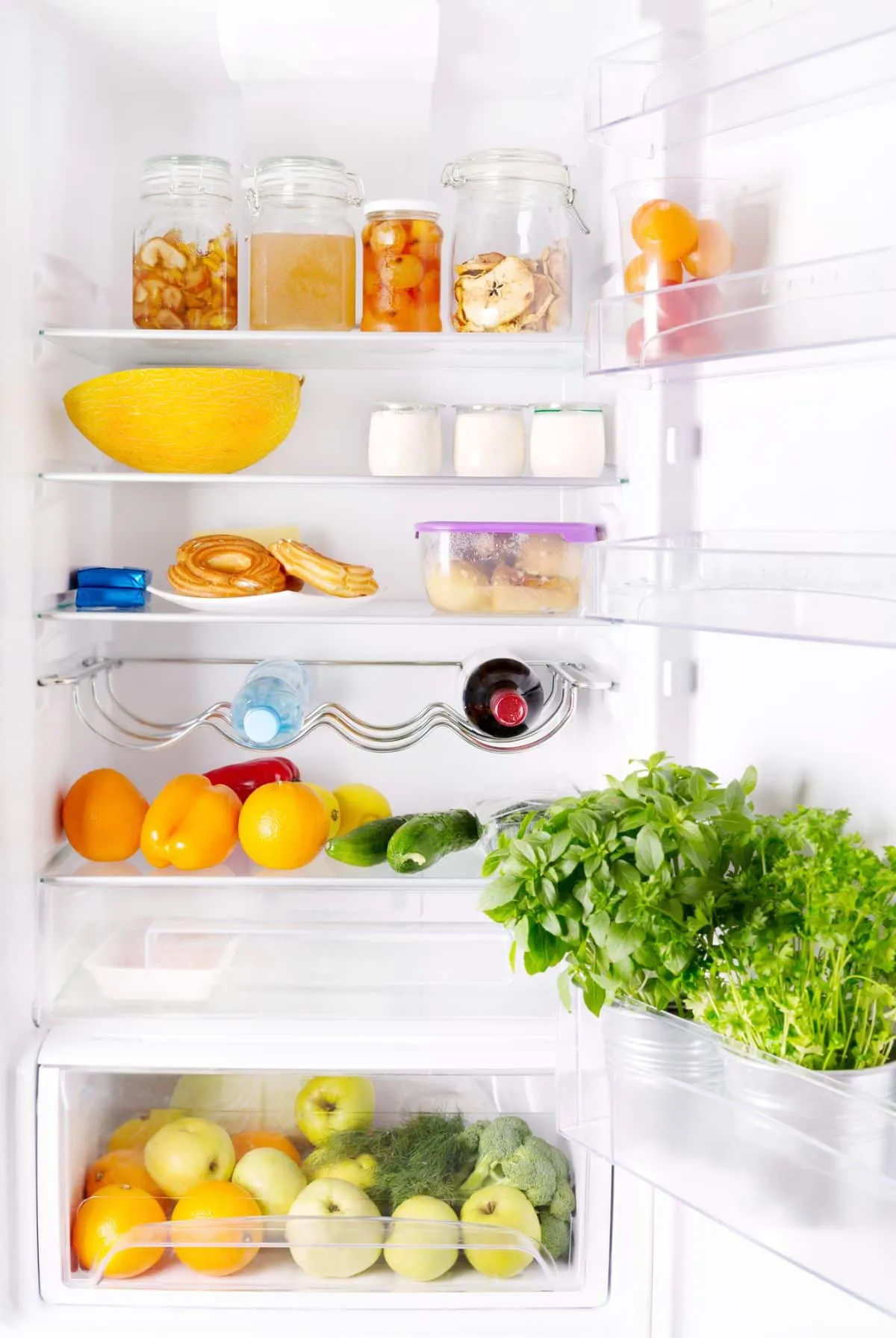 Белый холодильник с открытой дверью, наполненный продуктами