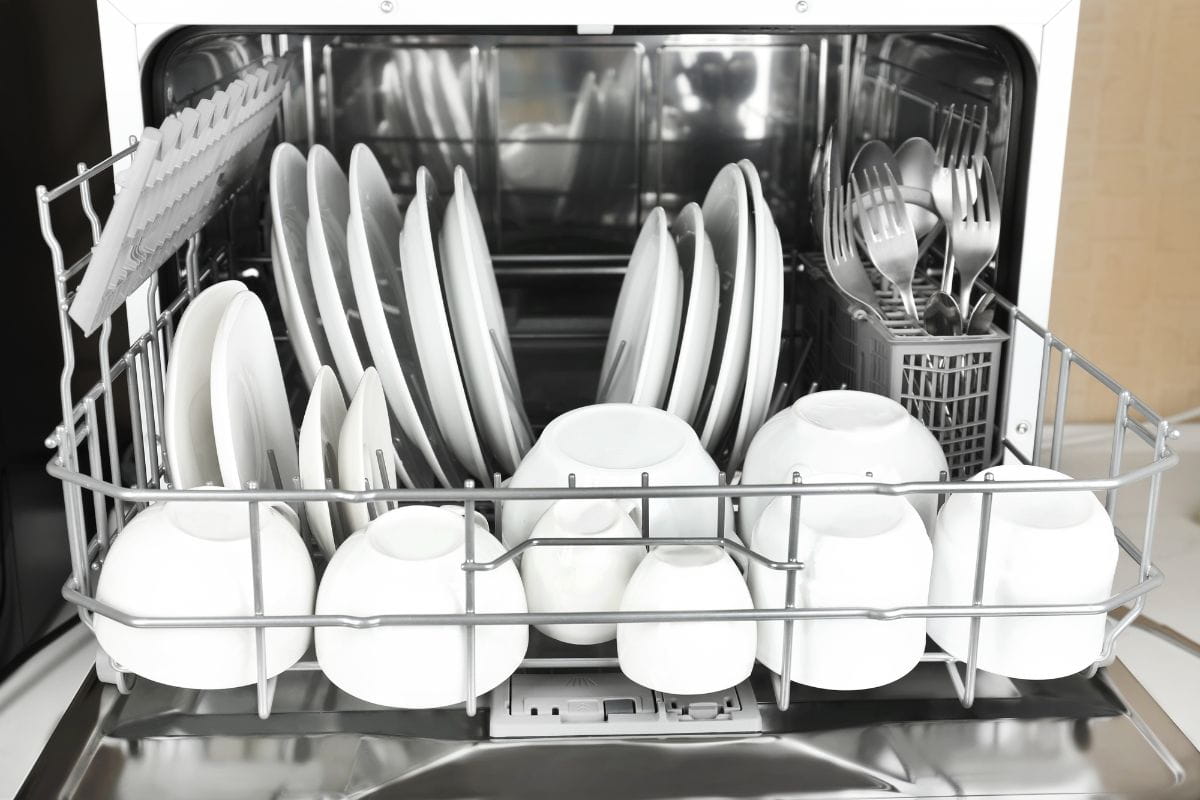 Открытая посудомоечная машина с чистой белой посудой